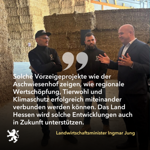 Minister Jung im Gespräch mit zwei Personen. Im Hintergrund viele Heuballen